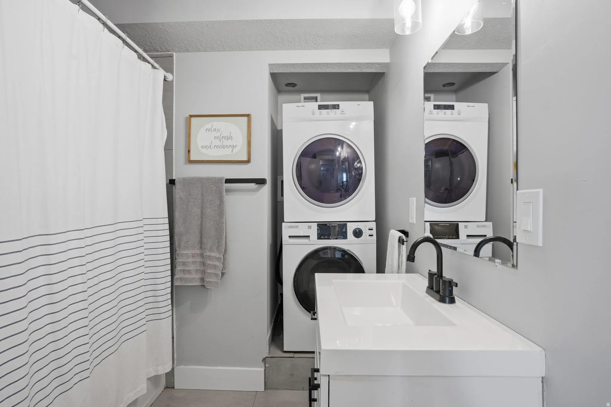 Furnished Unit #44 faces West. Laundry area with stacked washer and clothes dryer and a sink