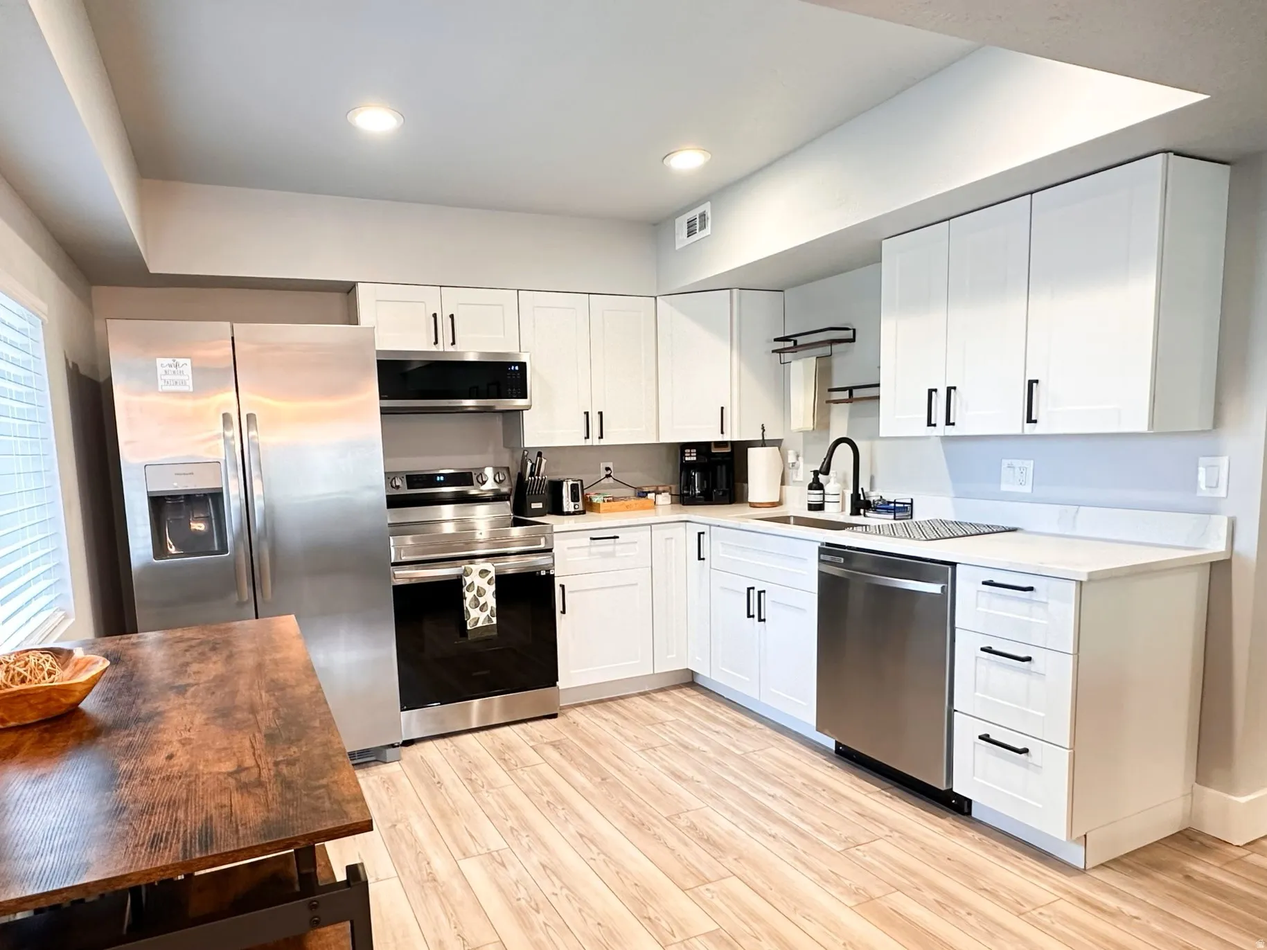 Furnished Unit #44 Kitchen featuring stainless steel appliances, white cabinetry, light wood finished floors, recessed lighting, and dark stone counters