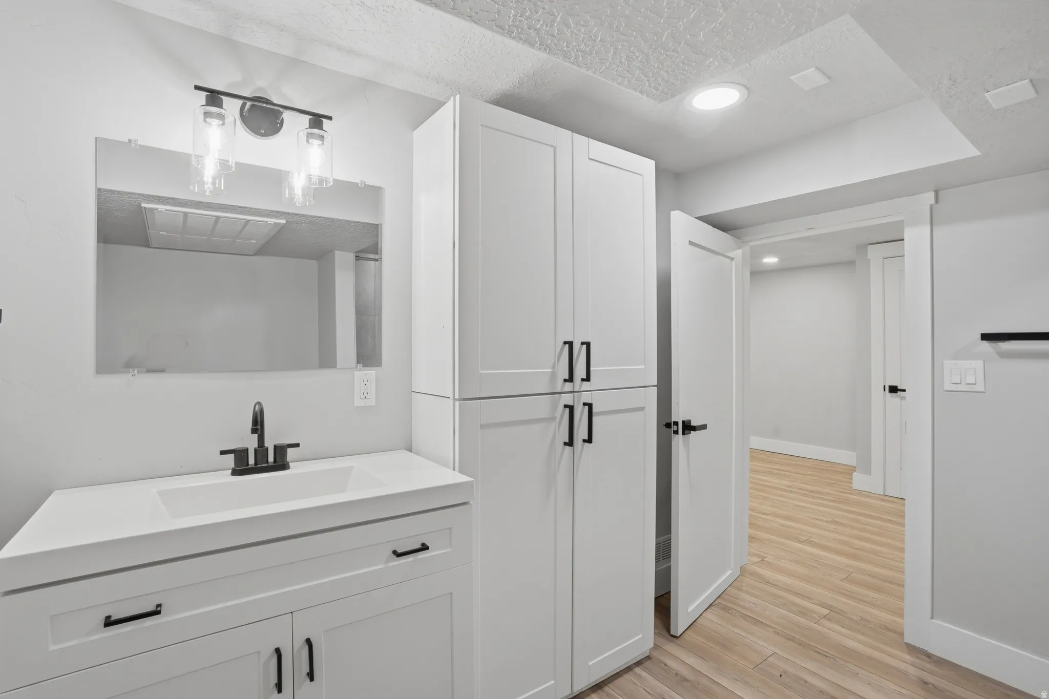 Unit #40 studio apartment with separate entrance. Bathroom featuring vanity, light wood-style floors, a textured ceiling, and recessed lighting