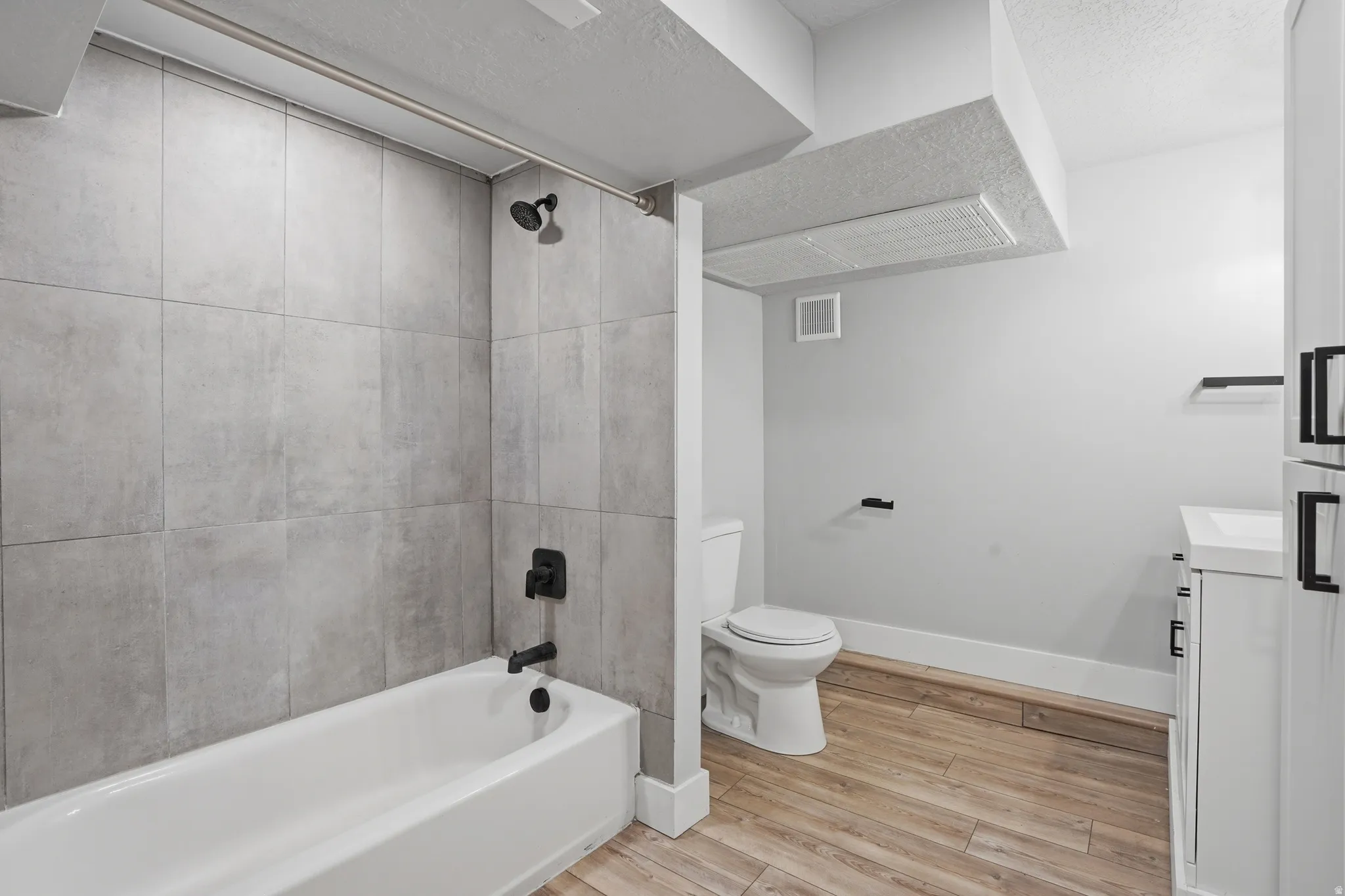Unit #40 studio apartment with separate entrance. Full bathroom featuring vanity, light wood-style flooring, bathtub / shower combination, and a textured ceiling