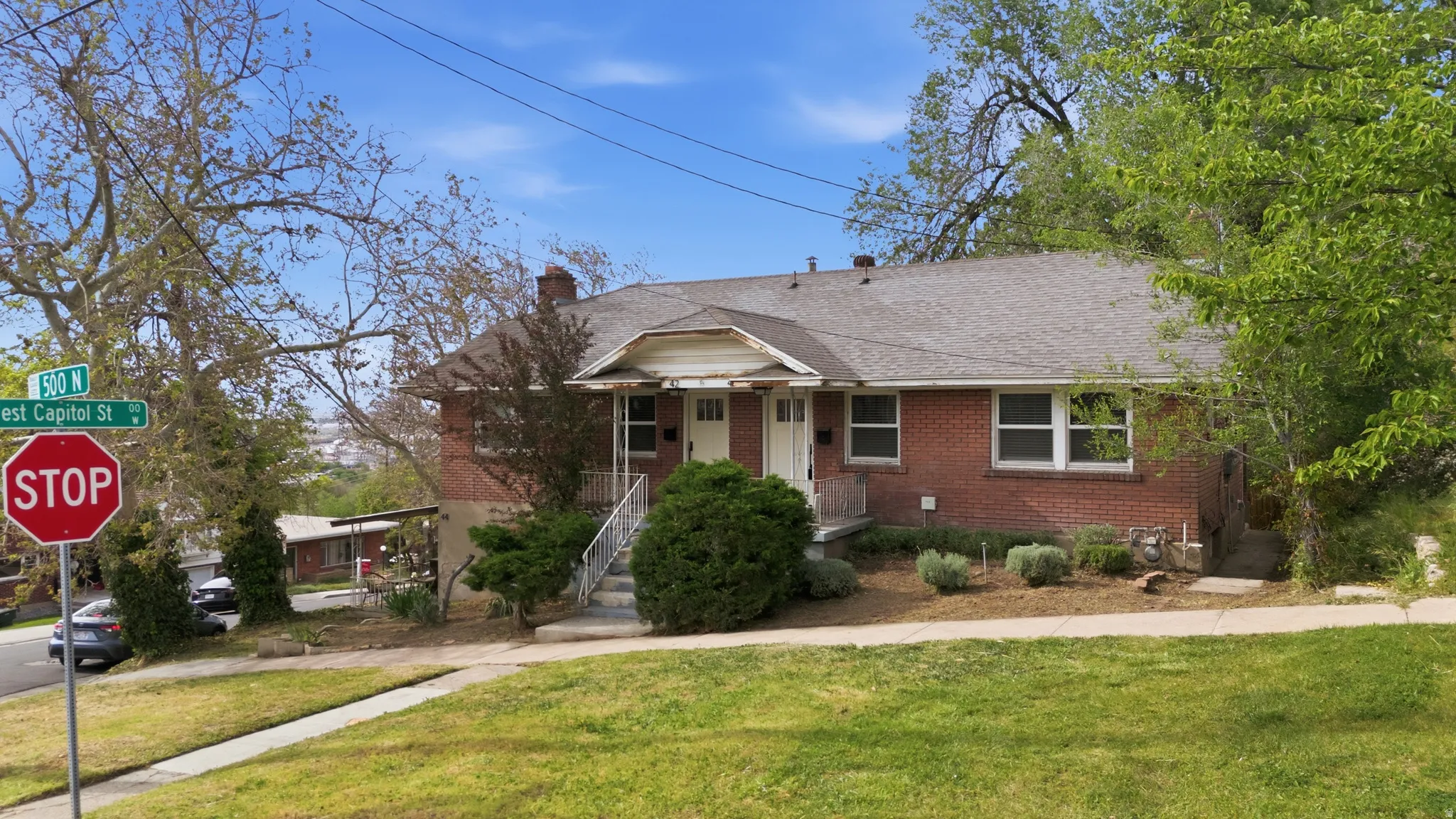 Triplex View of front 2 units #40 & #42 facade featuring a chimney, brick siding, a front yard, and a shingled roof