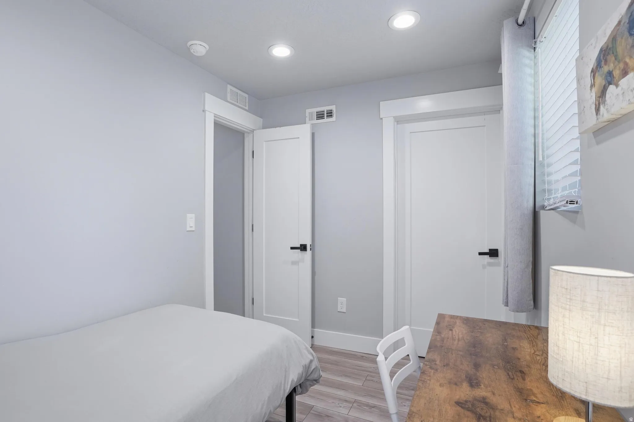 Furnished Unit #44 faces West. Bedroom with light wood-style flooring and recessed lighting
