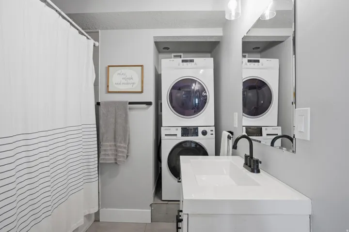 Furnished Unit #44 faces West. Laundry area with stacked washer and clothes dryer and a sink
