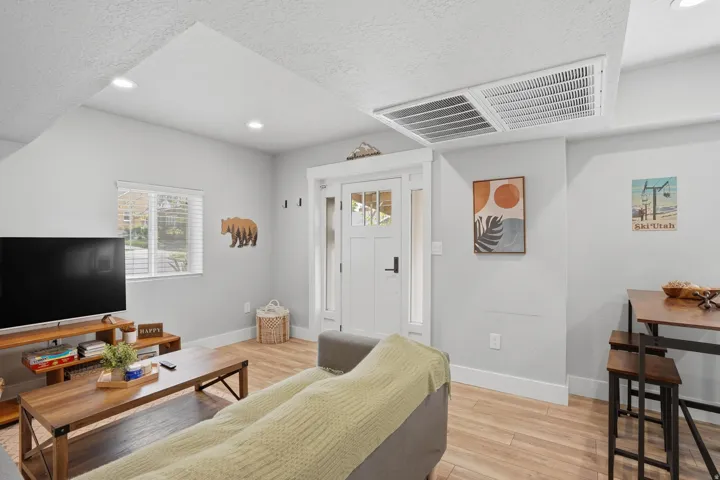 Furnished Unit #44 faces West. Living room featuring light wood-style flooring, recessed lighting, and a textured ceiling