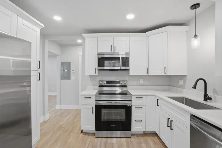 Unit #40 Kitchen with stainless steel appliances, white cabinetry, light stone countertops, and light wood-type flooring