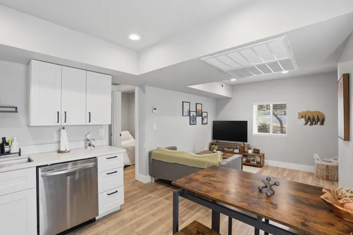 Furnished Unit #44 faces West. Kitchen with white cabinetry, stainless steel dishwasher, light wood-style floors, open floor plan, and recessed lighting