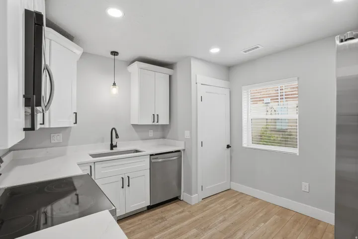 Unit #40 Kitchen featuring pendant lighting, white cabinets, light stone counters, and light wood-type flooring