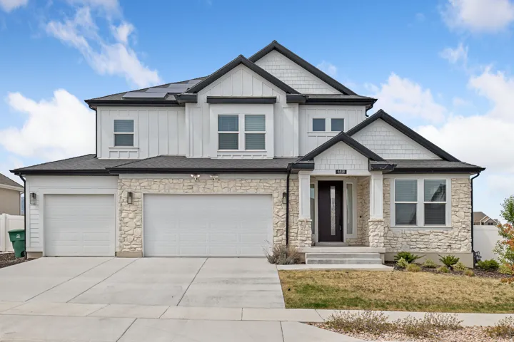 Craftsman-style house with solar panels, board and batten siding, stone siding, and concrete driveway