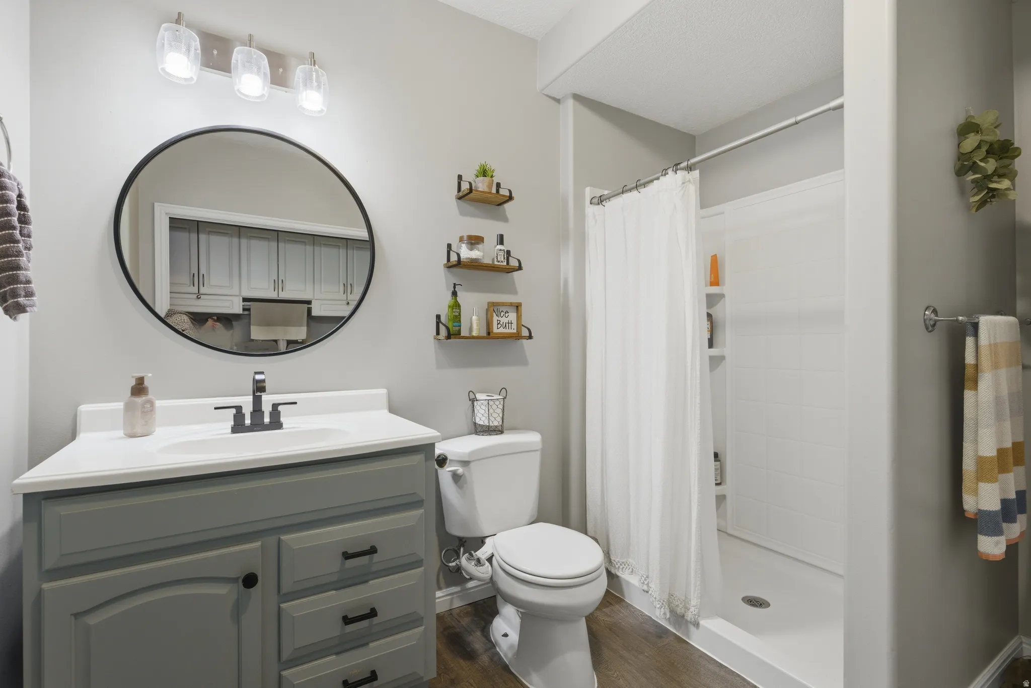 Full bath featuring vanity, a stall shower, and dark wood-style flooring