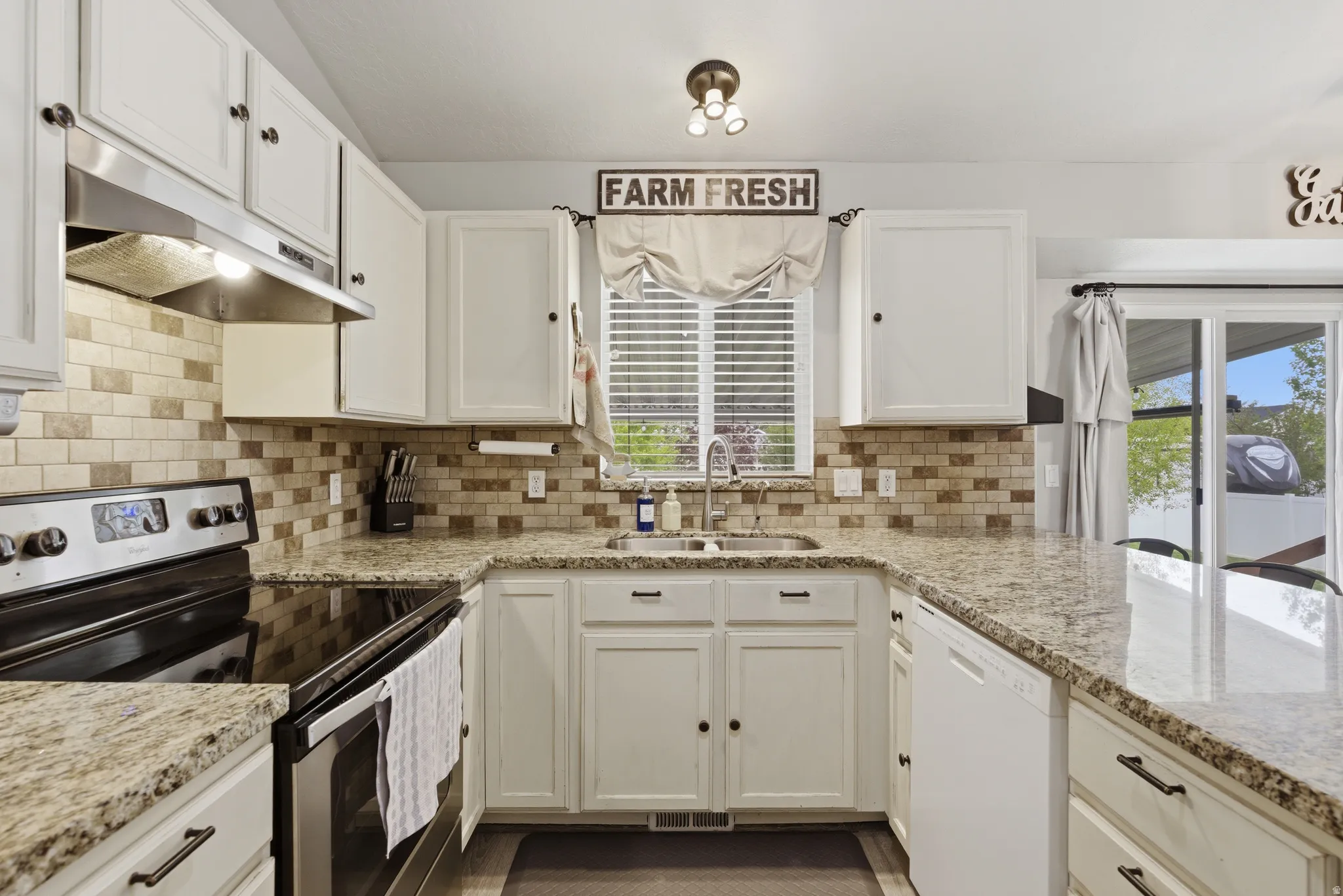 Kitchen with stainless steel range with electric stovetop, white cabinetry, and white dishwasher