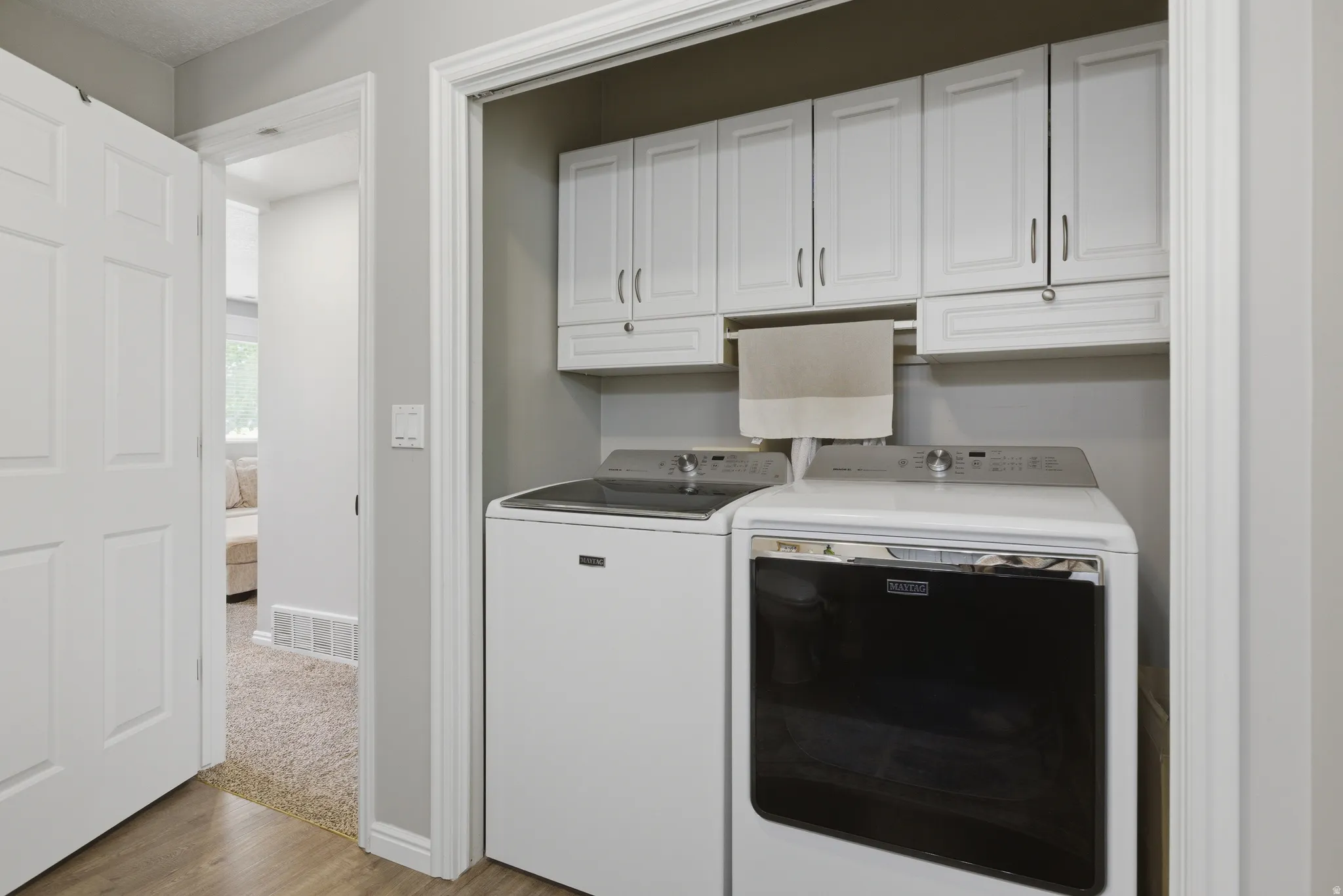 Laundry room featuring cabinet space, washing machine and clothes dryer, and light wood-style flooring