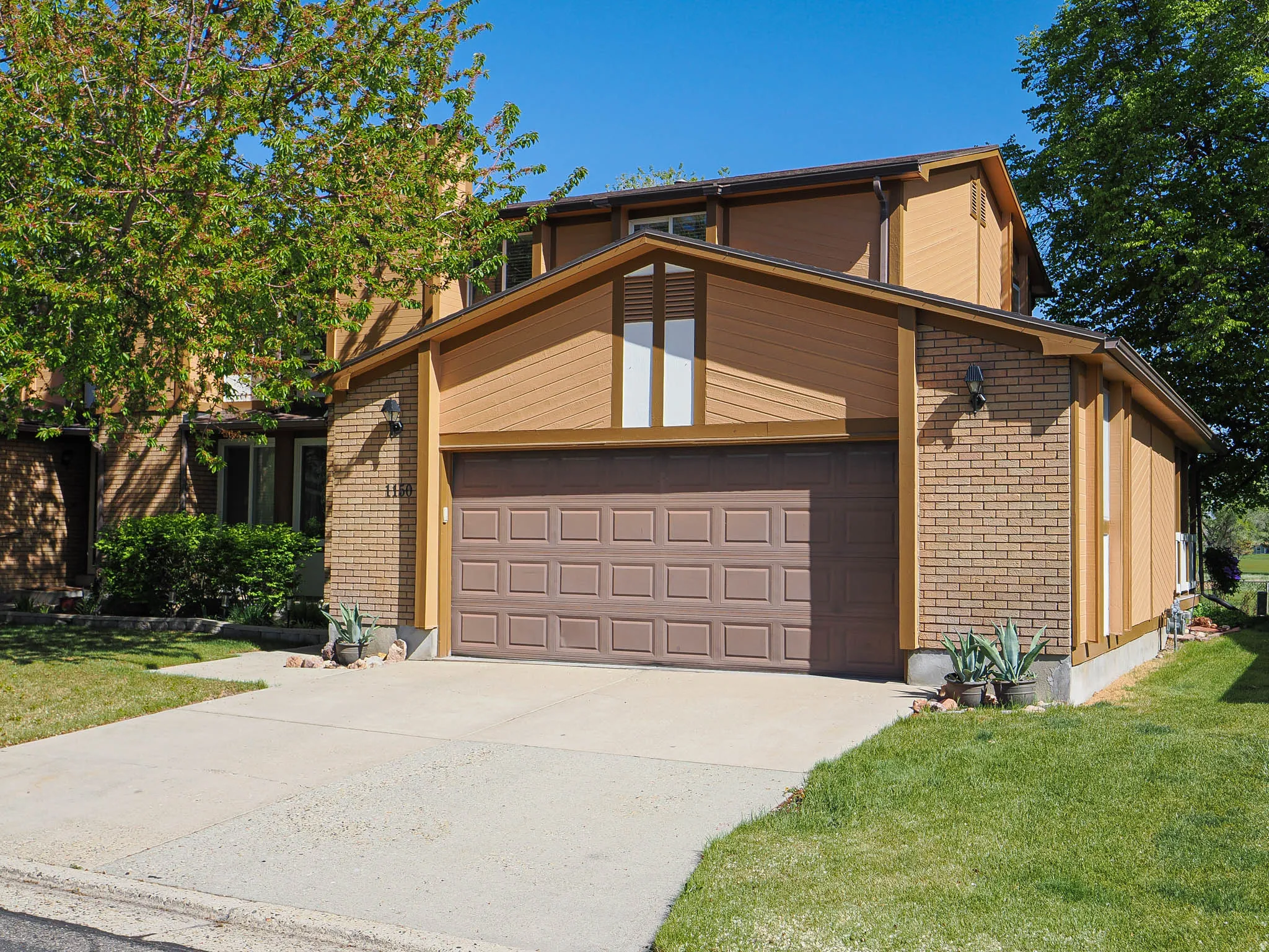 View of front of house featuring concrete driveway, an attached garage, brick siding, and a front lawn