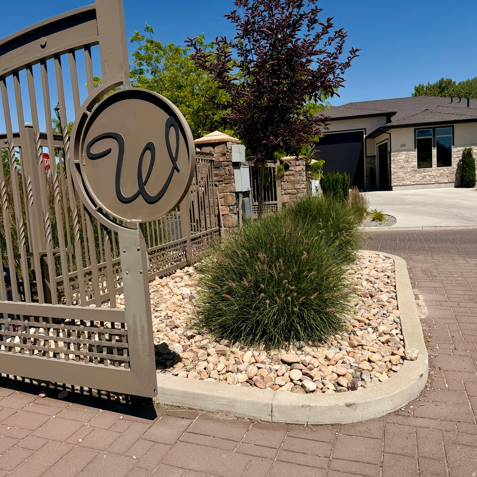 Gated entry with a decorative metal gate and stone pillars