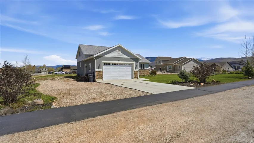 Craftsman-style home with a residential view, driveway, an attached garage, a mountain view, and a front yard