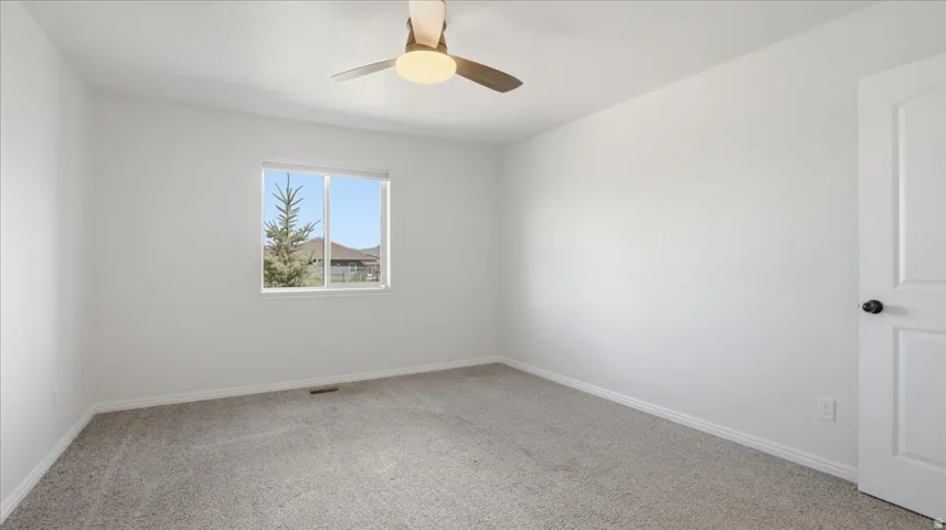 Carpeted spare room featuring baseboards and a ceiling fan
