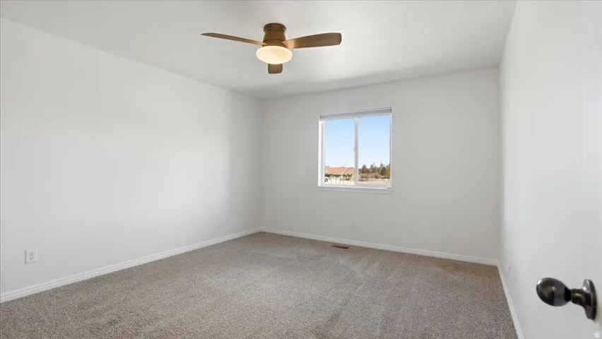 Spare room featuring carpet flooring and ceiling fan