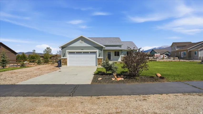 View of front of house featuring a front lawn, driveway, an attached garage, and a mountain view