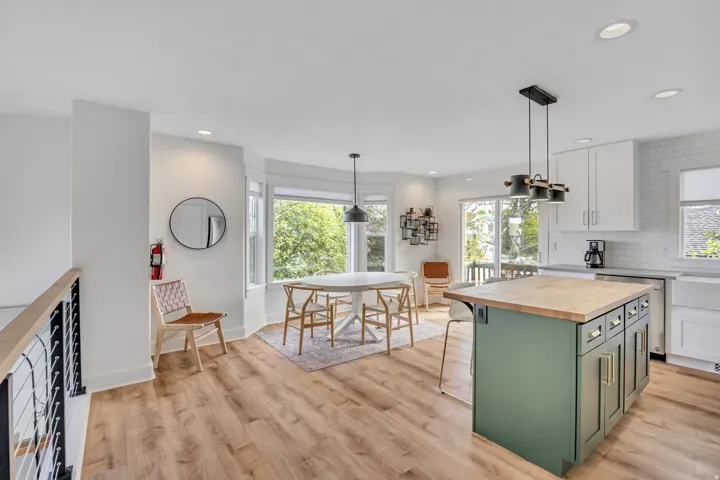 Kitchen featuring butcher block countertops, a kitchen breakfast bar, dual tone cabinets, decorative backsplash, and a center island