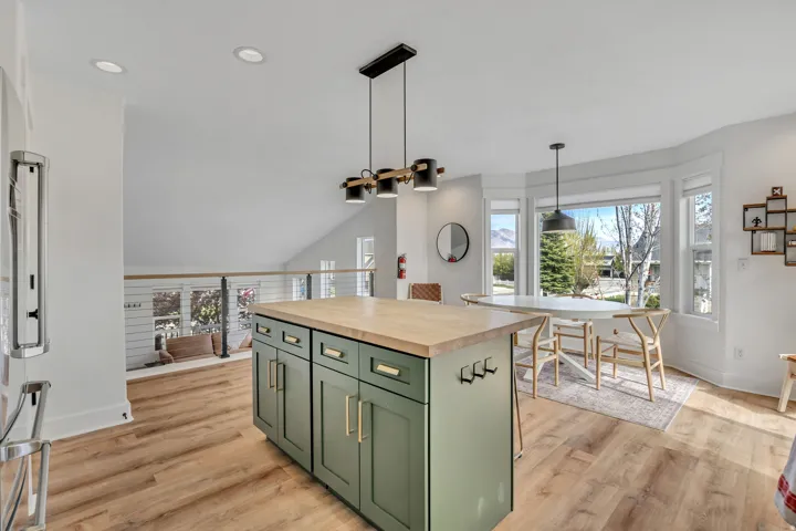 Kitchen featuring green cabinets, wooden counters, high end fridge, a kitchen island, and pendant lighting