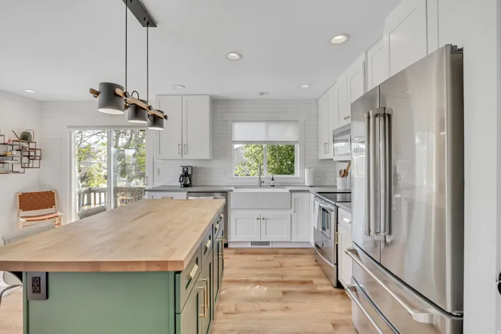 Dual tone kitchen featuring wooden counters, stainless steel appliances, two tone cabinets, a center island, and backsplash