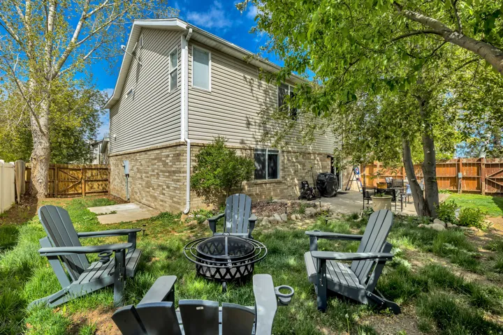 Back of house with an outdoor fire pit, a fenced backyard, a patio, brick siding, and a gate
