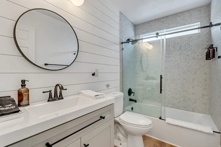 Bathroom with wood walls, vanity, combined bath / shower with glass door, and light wood-style floors