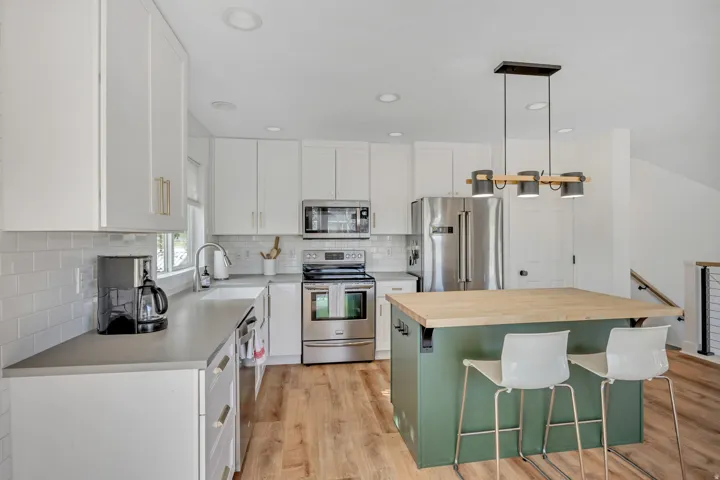 Kitchen featuring a kitchen bar, stainless steel appliances, a kitchen island, butcher block countertops, and light wood-style flooring
