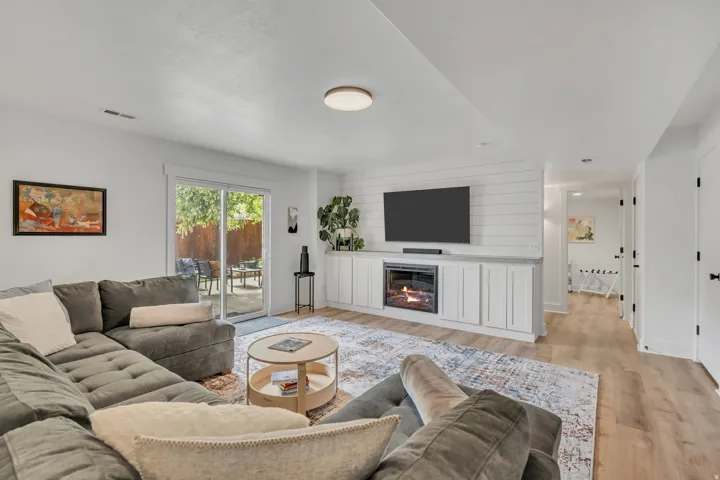 Living room with light wood-type flooring and a glass covered fireplace