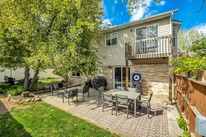 Rear view of property featuring a fenced backyard, a patio area, outdoor dining area, a balcony, and brick siding