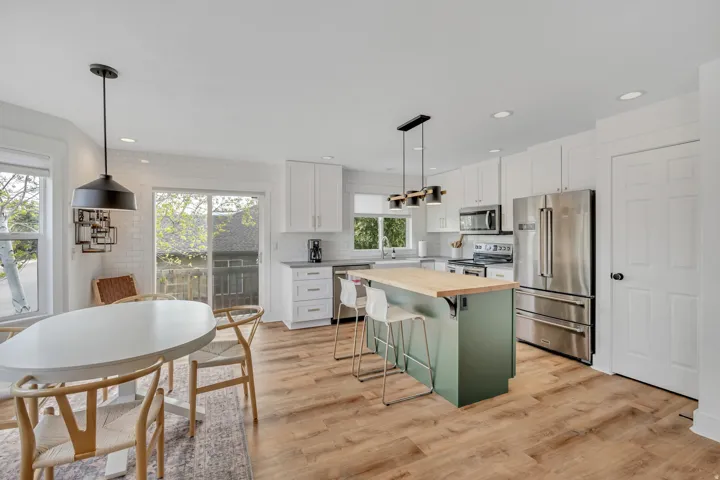 Kitchen featuring wood counters, stainless steel appliances, two tone color scheme, a kitchen breakfast bar, and tasteful backsplash