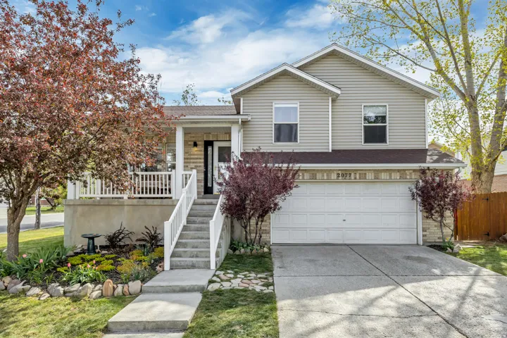 Tri-level home with concrete driveway, a shingled roof, an attached garage, and a porch