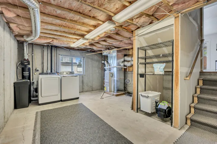 Below grade area with heating unit, separate washer and dryer, and a water softener system