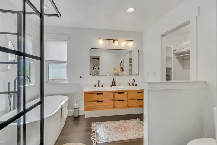 Bathroom featuring double vanity, a freestanding tub, dark wood-type flooring, and recessed lighting