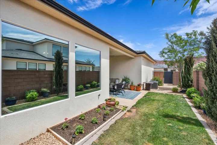 Fenced backyard featuring a patio area and a vegetable garden