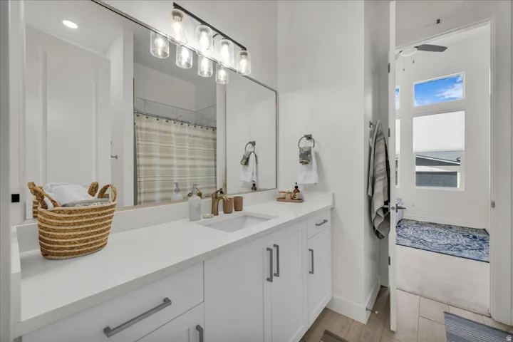 Full bath featuring vanity, a shower with shower curtain, light wood-style floors, and ceiling fan