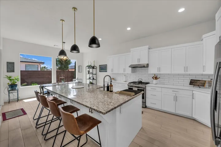 Kitchen featuring light stone countertops, a breakfast bar, light wood finished floors, and white cabinets