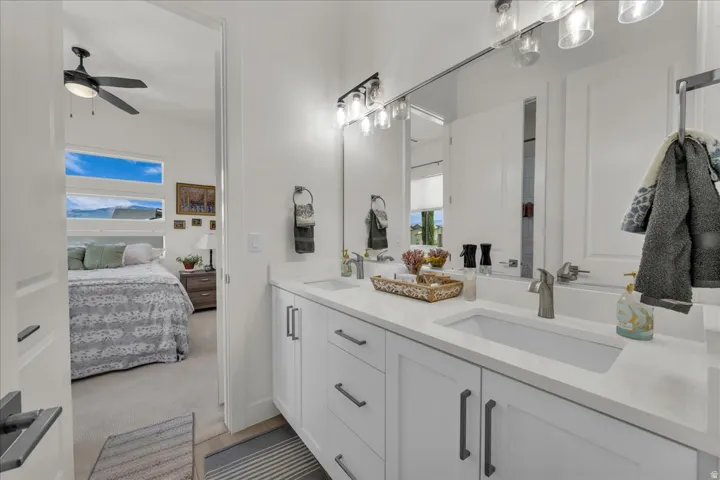 Bathroom featuring double vanity, connected bathroom, ceiling fan, and light carpet