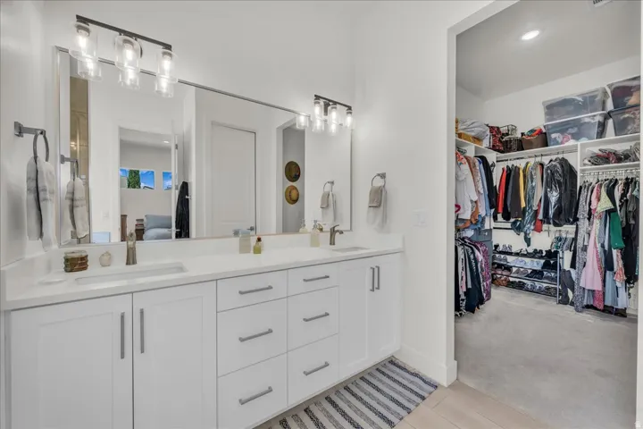 Full bath with double vanity, connected bathroom, recessed lighting, and a spacious closet