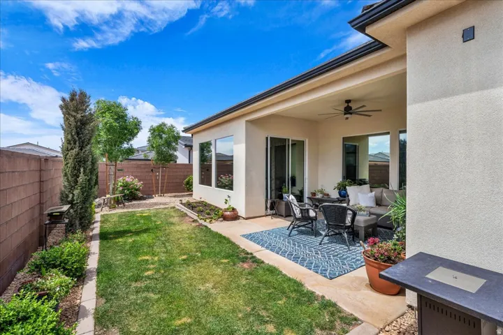 Fenced backyard featuring ceiling fan, an outdoor lounge area, and a patio area