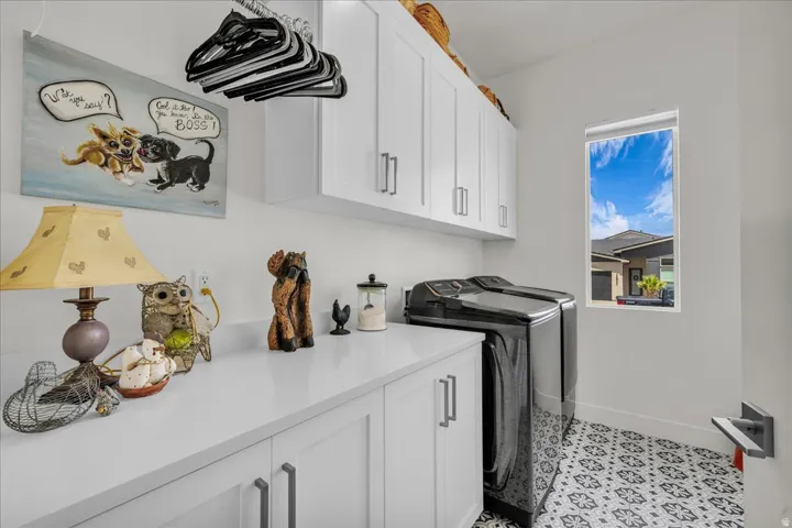 Laundry room featuring cabinet space, washing machine and dryer, and light tile patterned floors