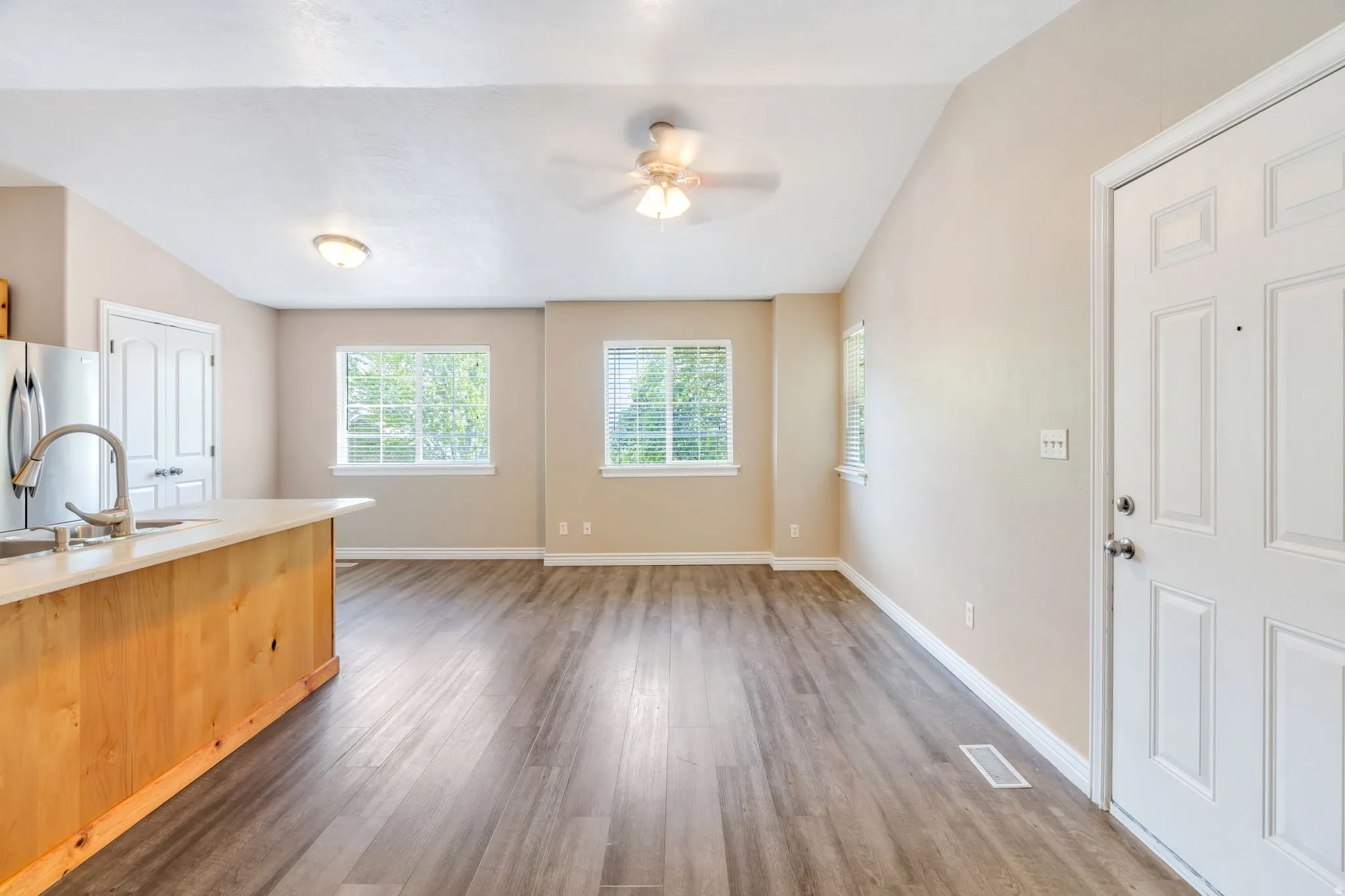 Kitchen featuring vaulted ceiling, freestanding refrigerator, light countertops, plenty of natural light, and dark wood finished floors