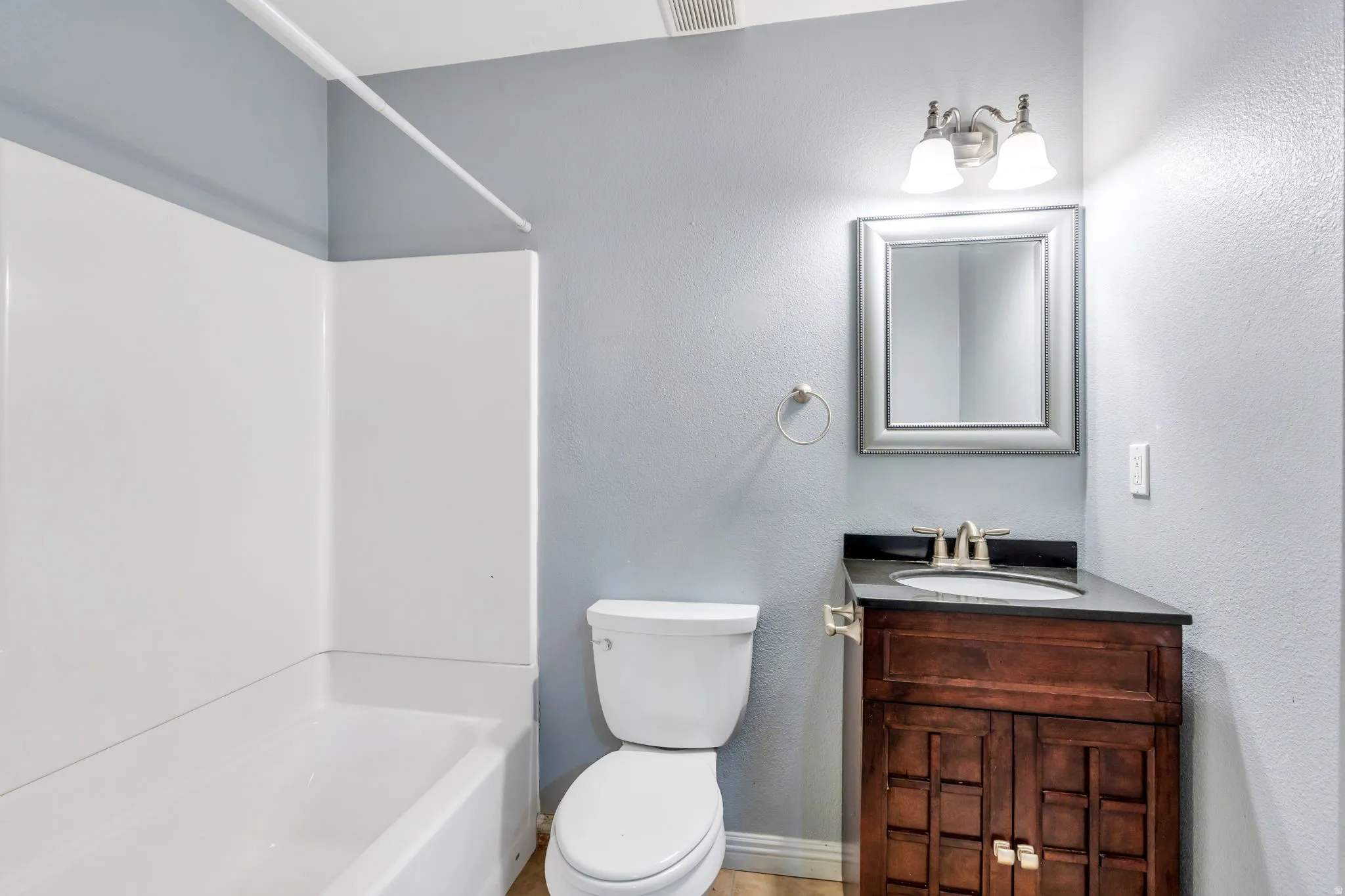 Full bath featuring vanity, shower / bathtub combination, and a textured wall