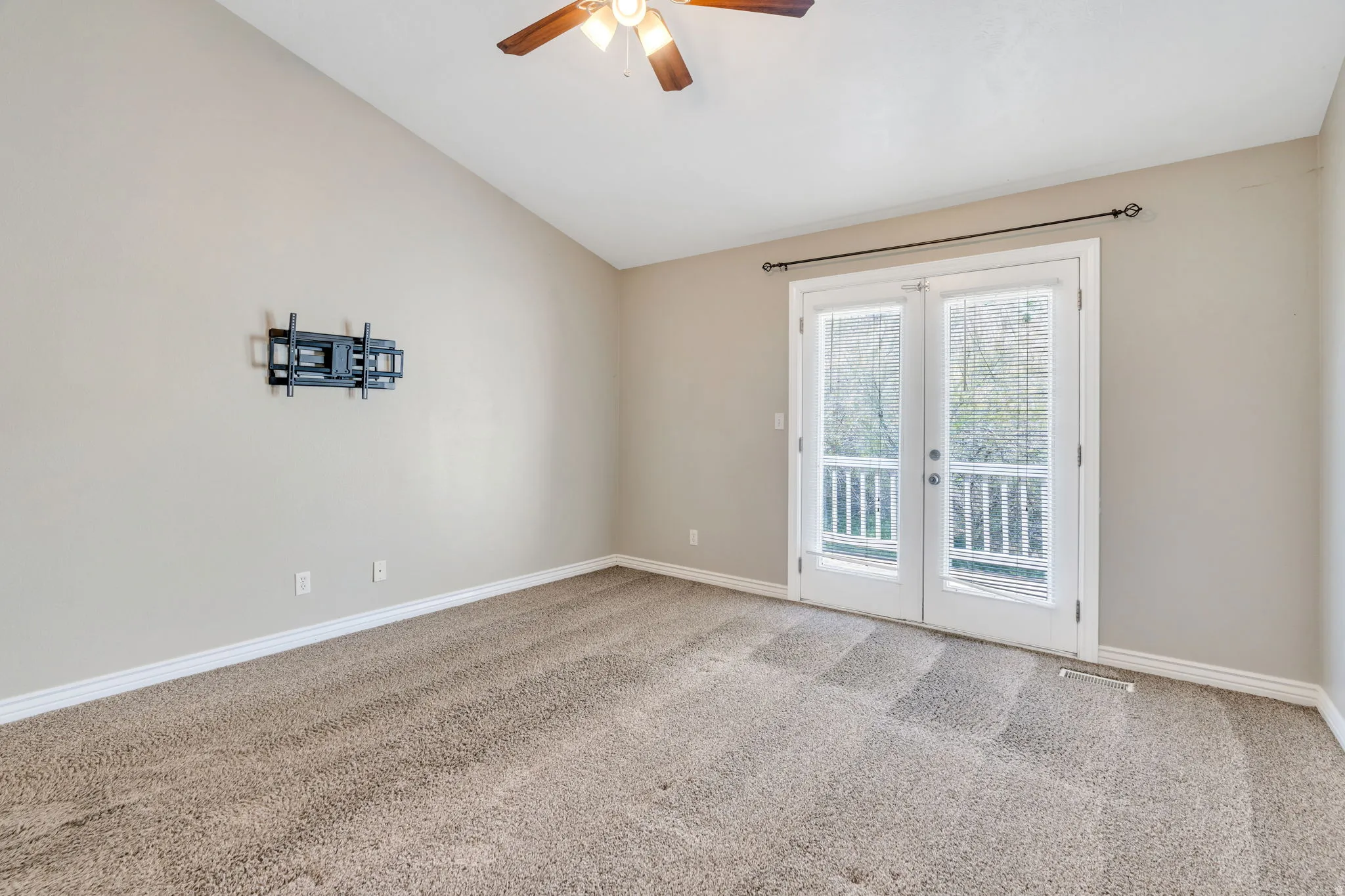 Carpeted empty room featuring french doors, lofted ceiling, and a ceiling fan