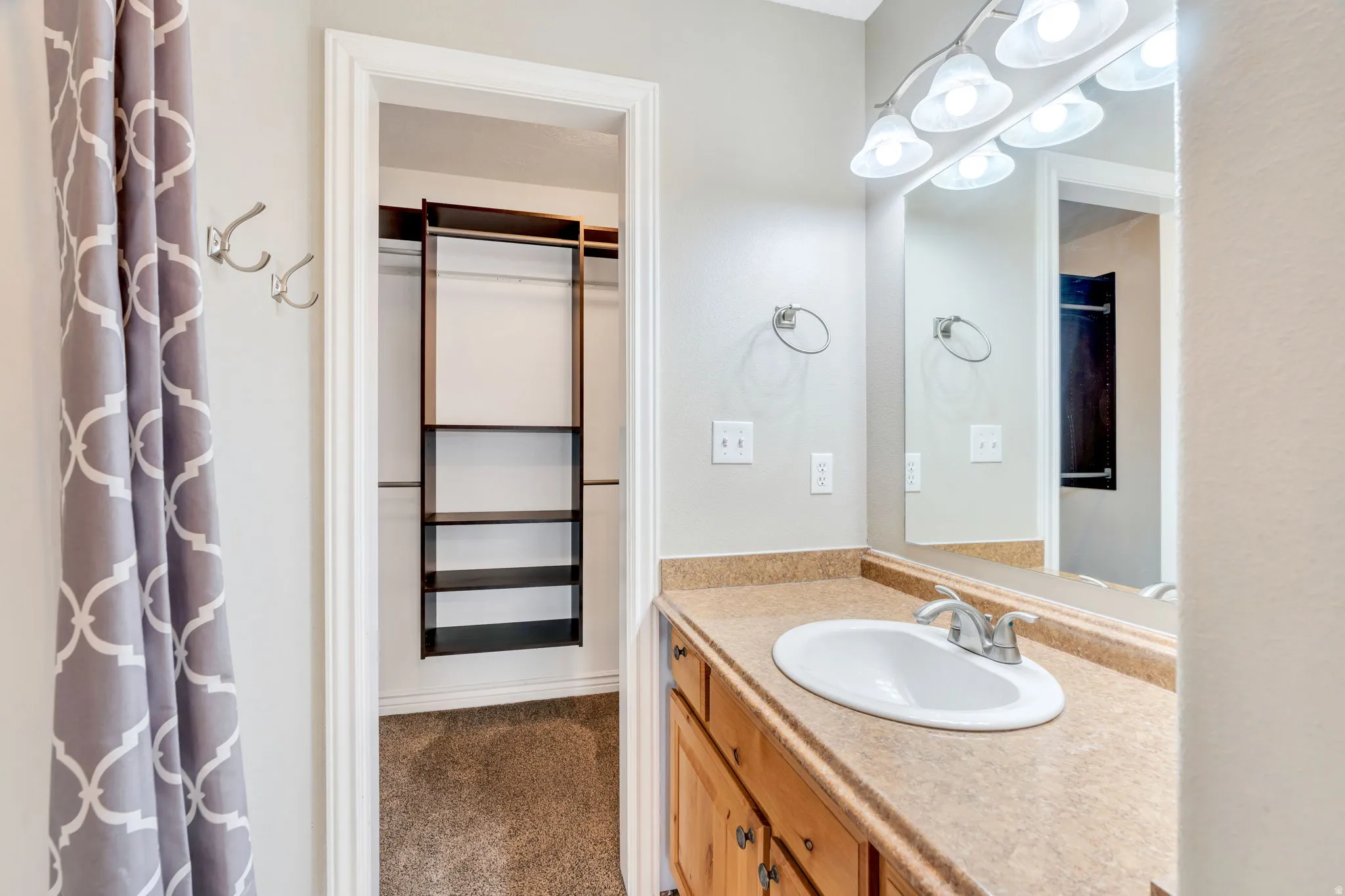 Full bathroom with vanity, a walk in closet, and dark carpet