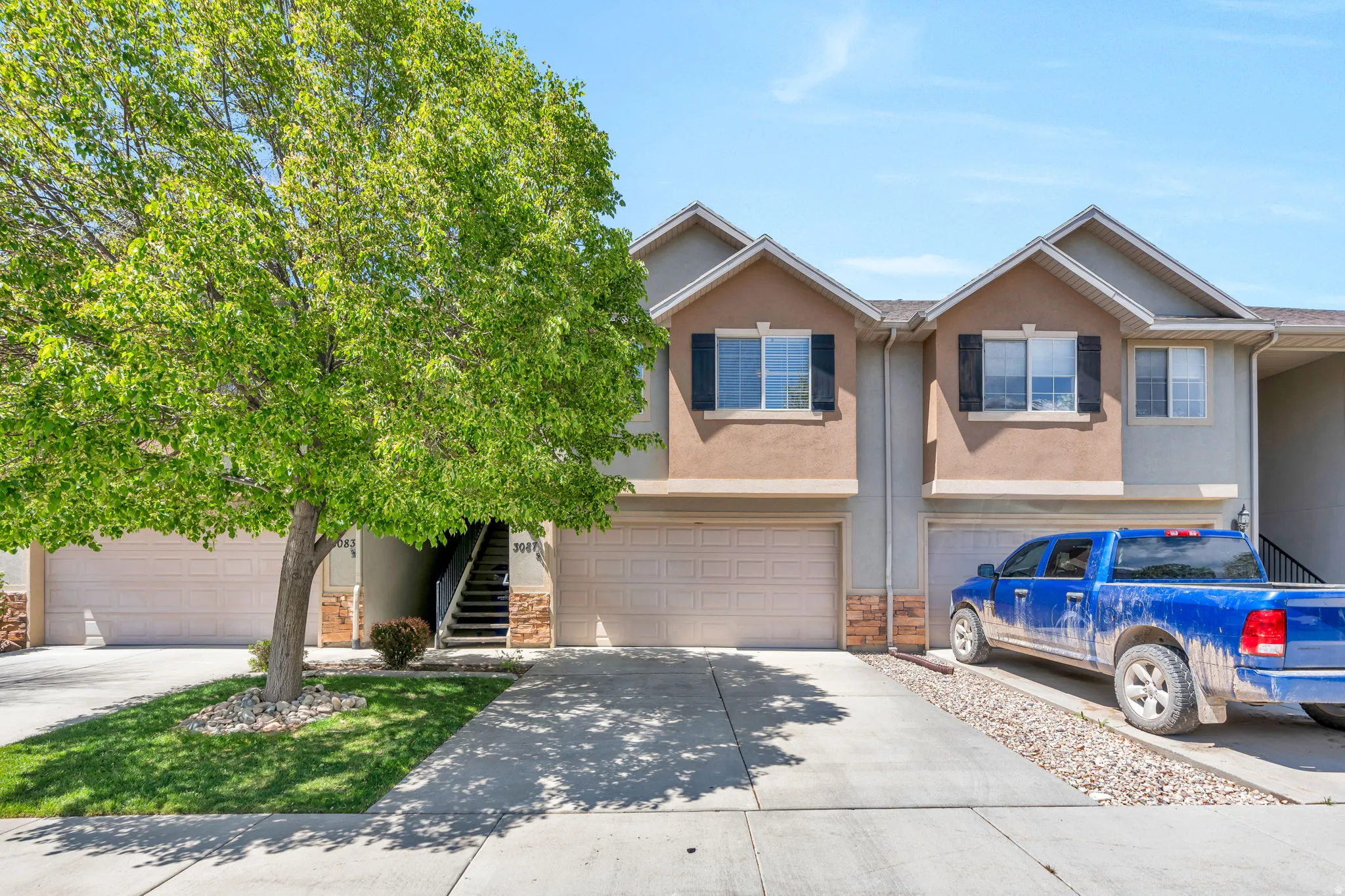 View of front facade featuring an attached garage, stucco siding, concrete driveway, and stone siding