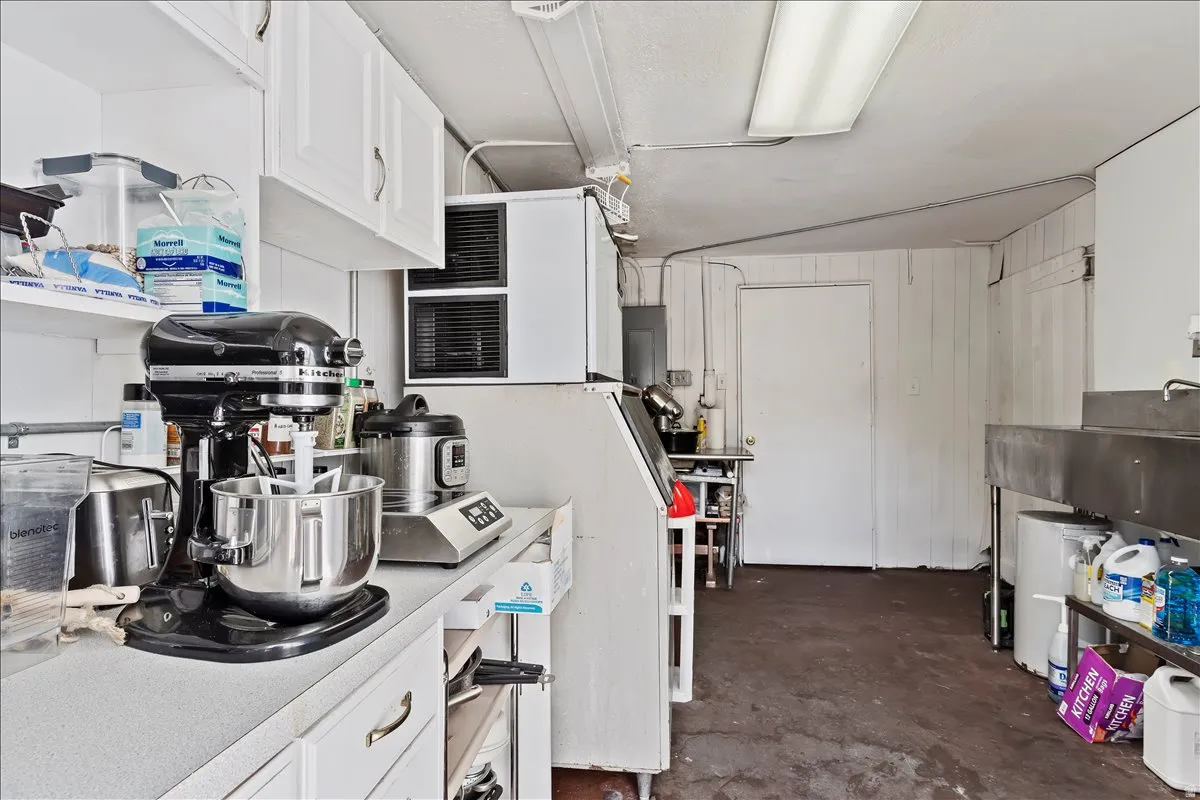 Kitchen with white cabinets, light countertops, electric panel, and white refrigerator