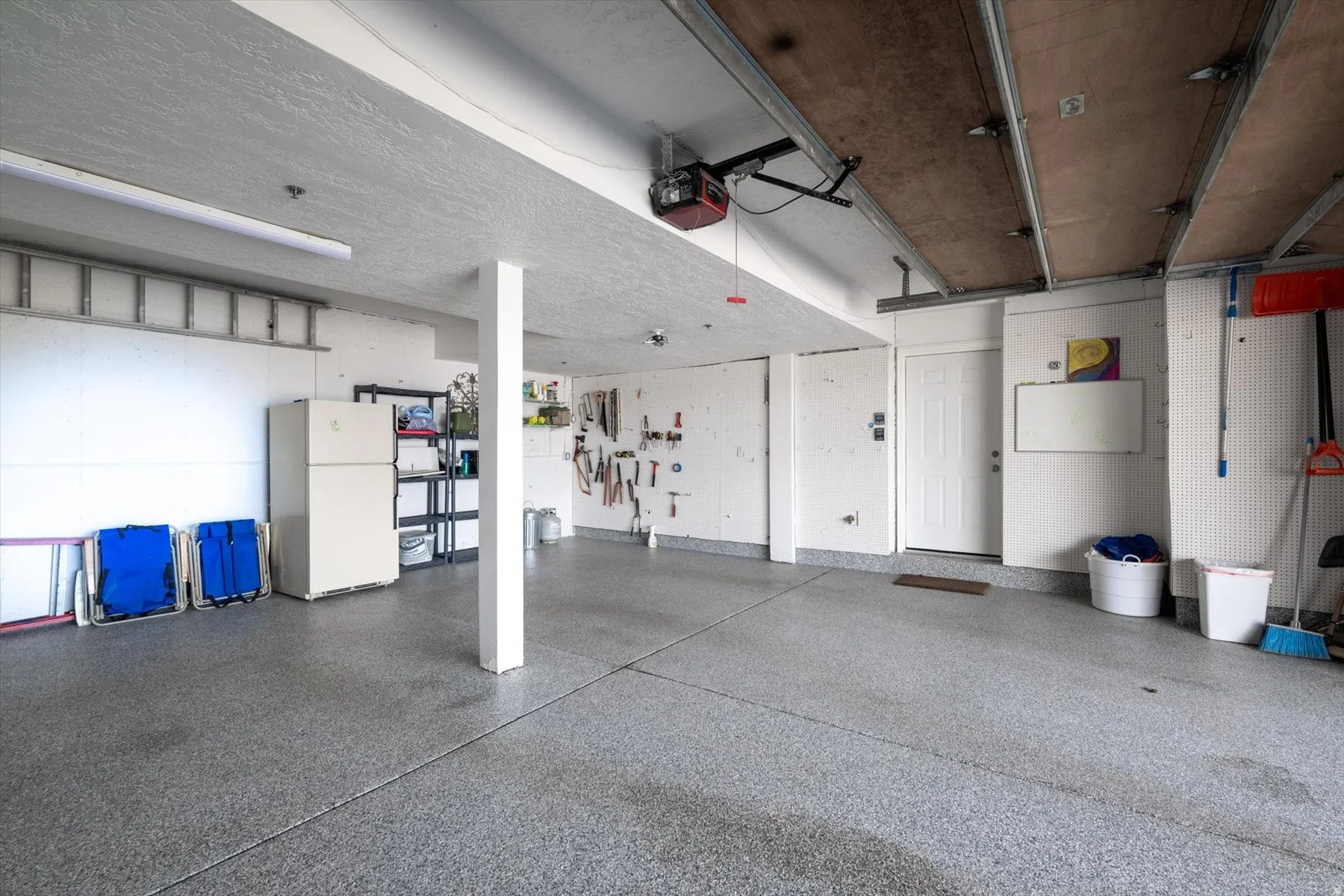 Garage featuring freestanding refrigerator and a garage door opener