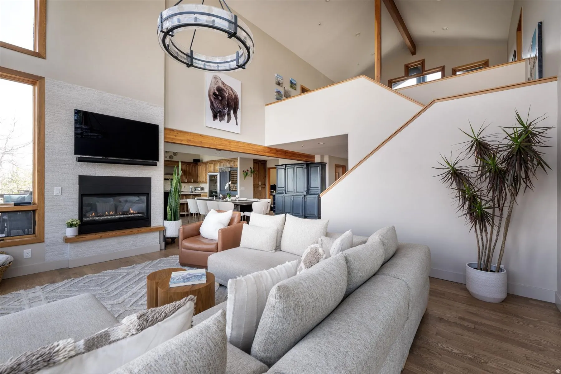Living area with a glass covered fireplace, wood finished floors, lofted ceiling, and hanging lights