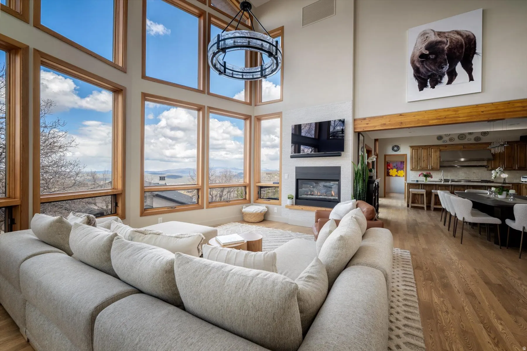 Living room with a high ceiling, a glass covered fireplace, and wood finished floors