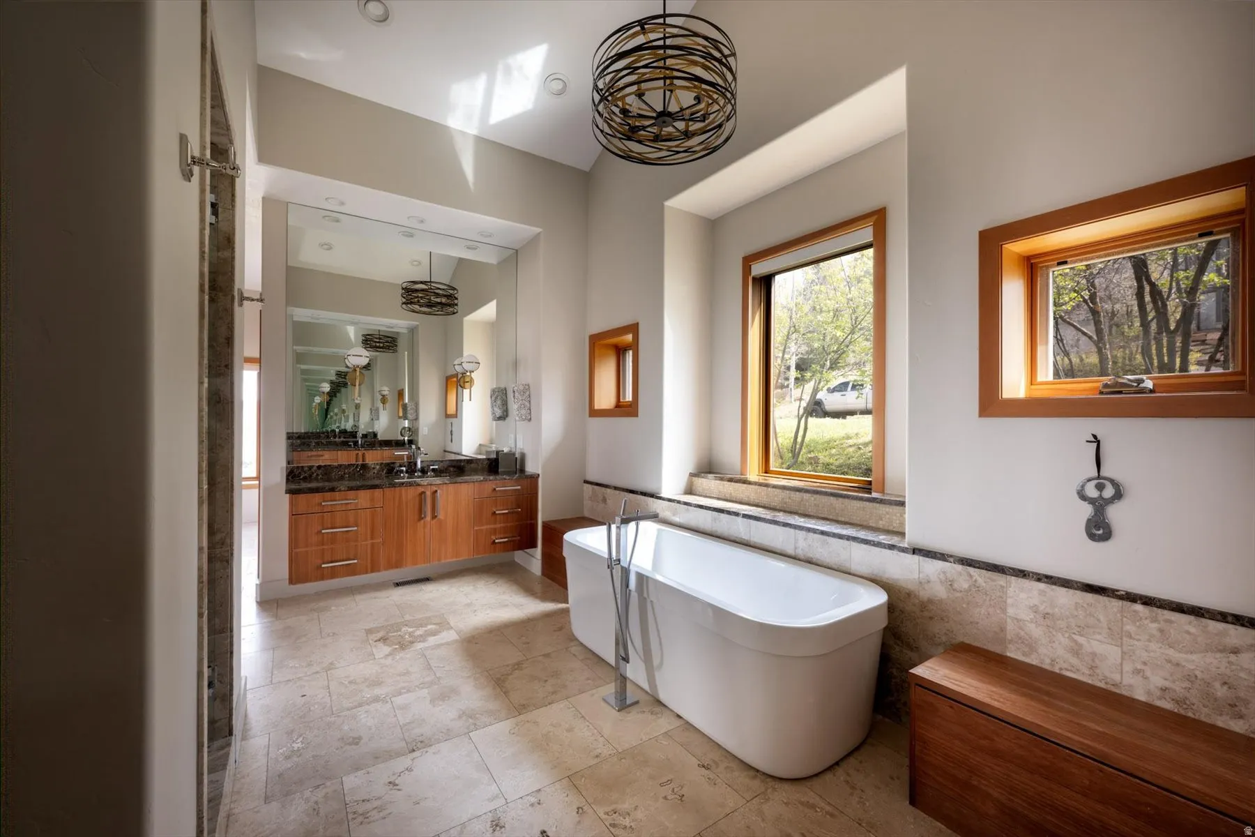 Bathroom with vanity, a freestanding tub, tile walls, and hanging lights